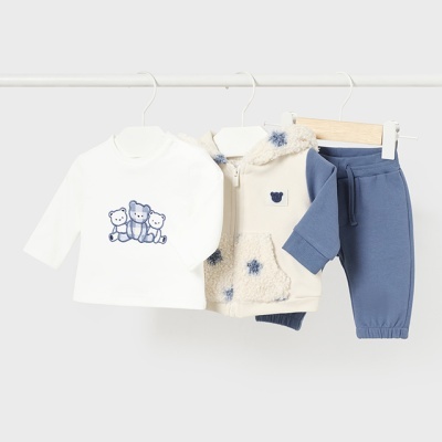 Conjunto de roupa infantil com camisola branca, casaco bege com pelo e estrelas azuis, e calças azuis pendurados em cabides.
