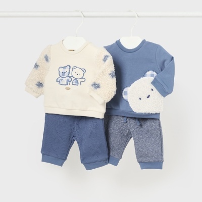 Conjuntos de roupa para bebé com sweatshirts e calças em azul e bege pendurados em cabides.