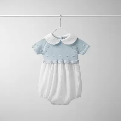 Macacão branco e azul para bebé com gola branca pendurado num cabide