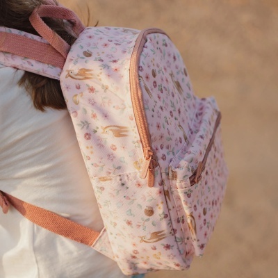 Mochila rosa com padrão de flores e animais usada por criança