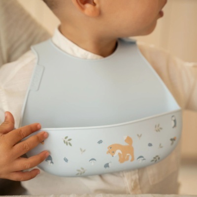 Babete de silicone azul claro com padrão de raposa e elementos naturais