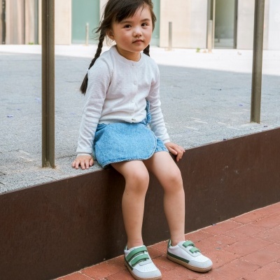 Criança sentada numa mureta com roupa casual e sapatilhas