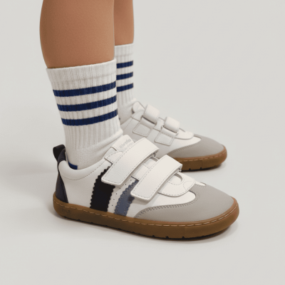Sapatilhas infantis brancas com detalhes cinza e azul escuro e meias brancas com riscas azuis