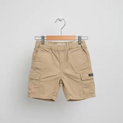 Calções cargo bege para criança pendurados num cabide de madeira