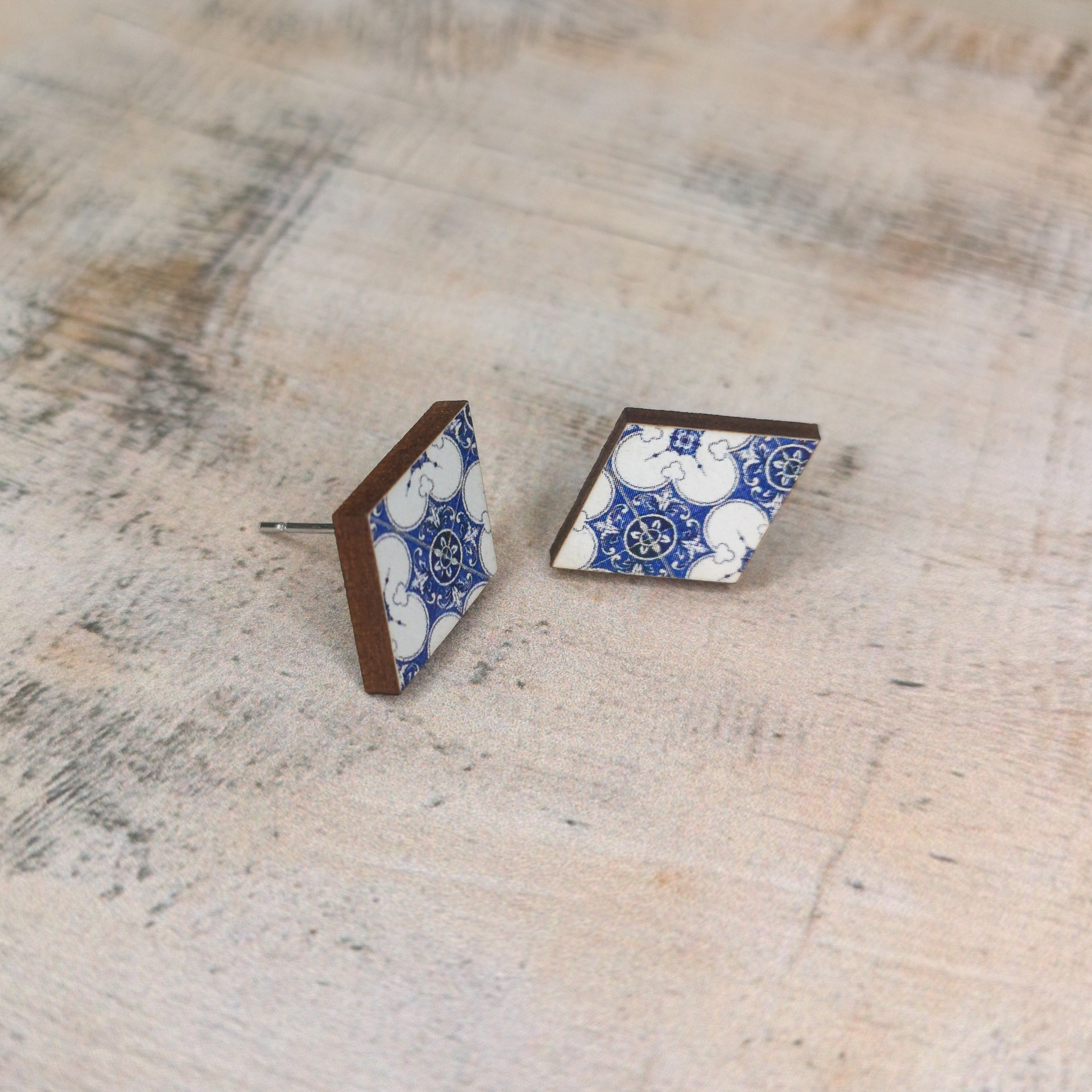 Brincos Alcobaça Brincos losango azul e branco em base de madeira sobre superfície clara.