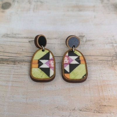 Brincos de madeira com padrão geométrico colorido em fundo de madeira clara