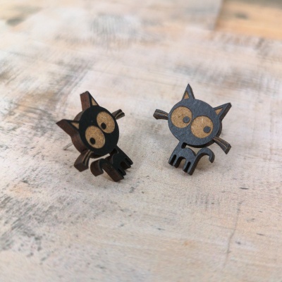Brincos de gato em madeira preta e castanha clara sobre superfície de madeira.