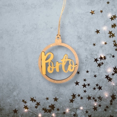 Enfeite redondo pendurado com a palavra 'Porto' em madeira, estrelas metálicas e luzes decorativas num fundo cinza.