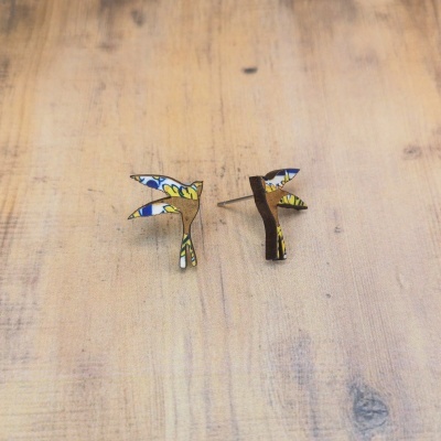 Brincos de madeira com padrão colorido sobre superfície de madeira clara