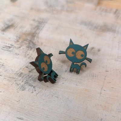 Brincos de gato estilizado em madeira azul e bege sobre superfície rústica