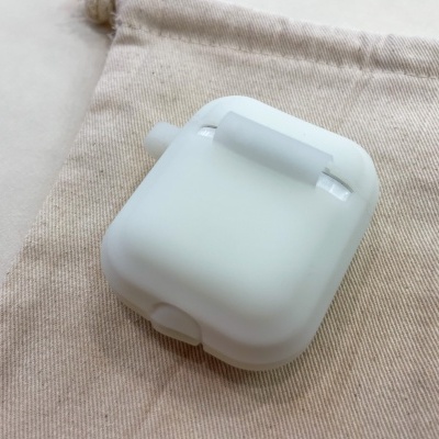 Estojo branco fosco para auriculares sem fios sobre saco de pano bege