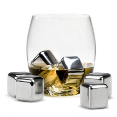 Copo de vidro com bebida âmbar e cubos de gelo metálicos prateados