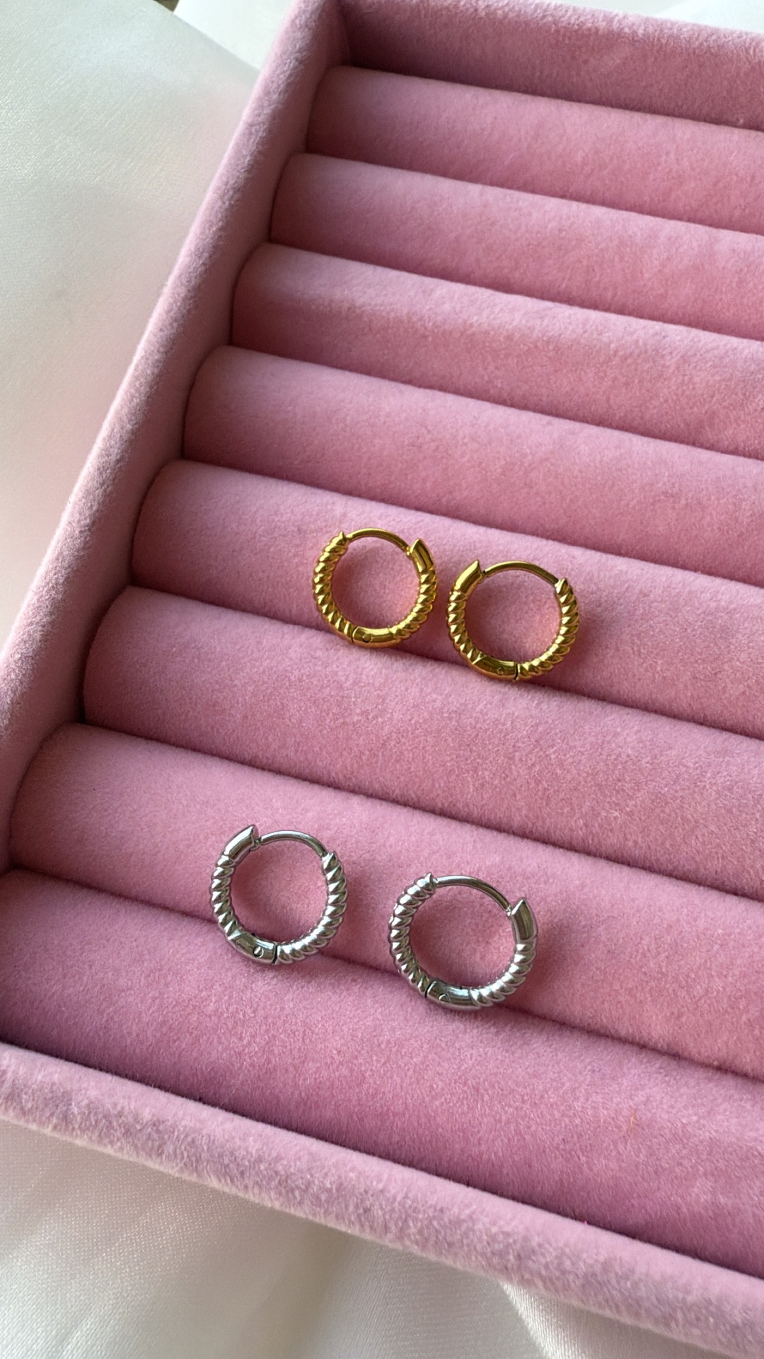 Quatro brincos de argola, dois dourados e dois prateados, em caixa de veludo rosa.