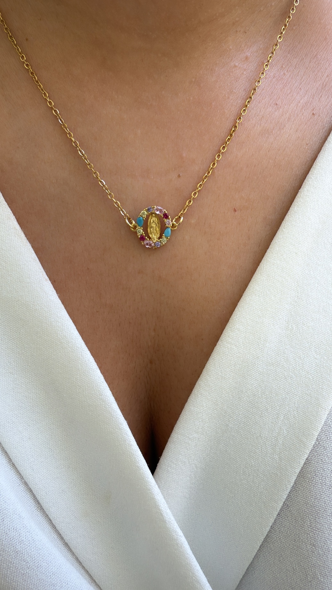 Colar dourado com pendente oval colorido numa blusa branca