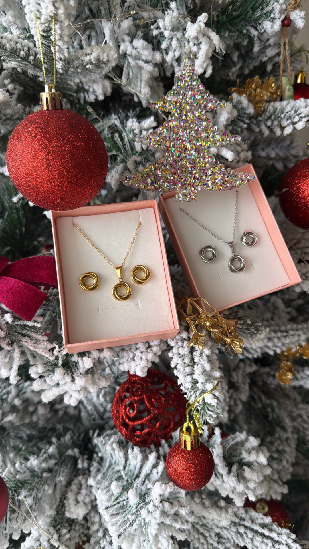 Conjuntos de joias douradas e prateadas num pinheiro de Natal nevado com bolas e enfeites vermelhos