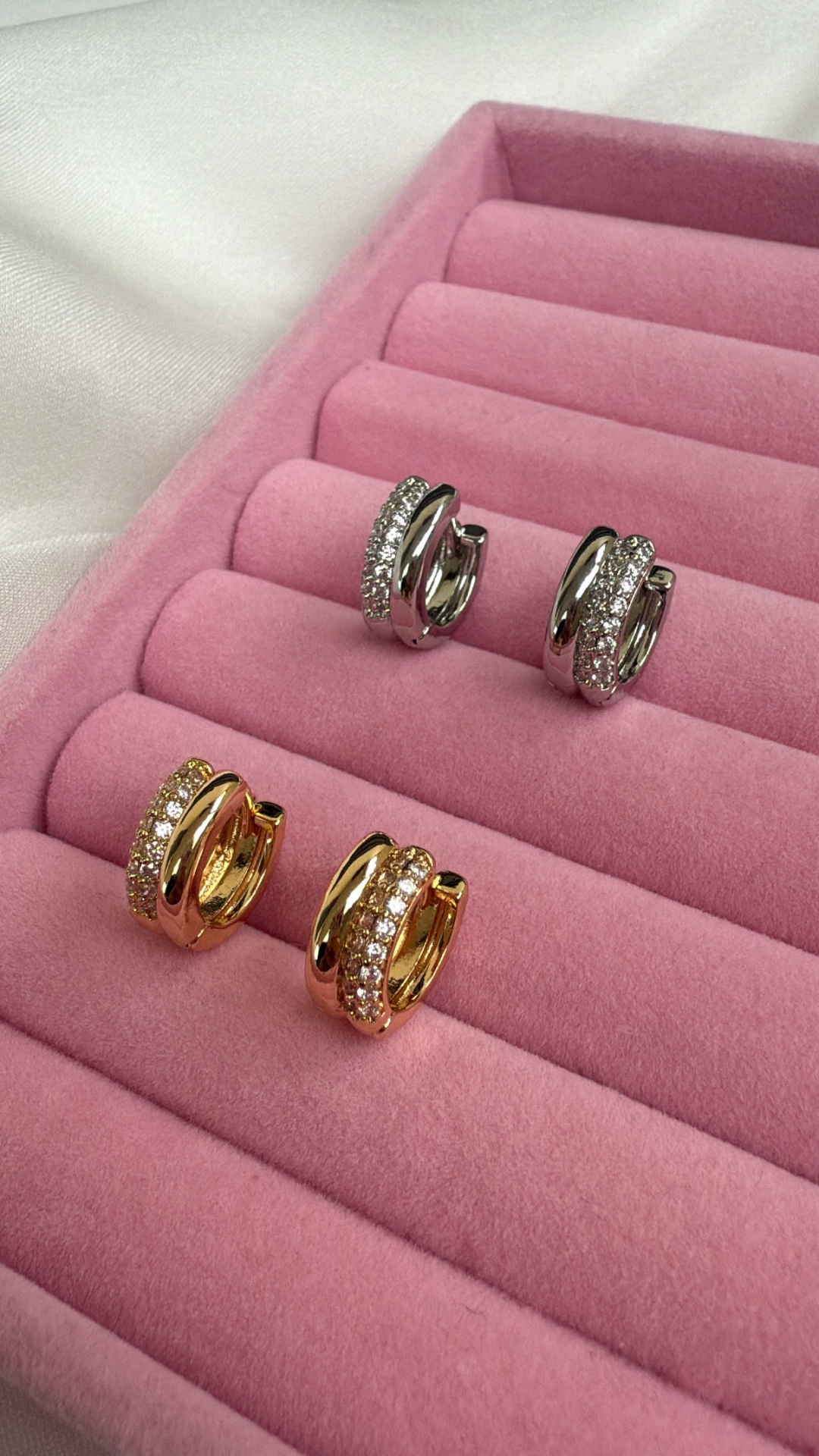 Brincos dourados e prateados com pedras em caixa de veludo rosa