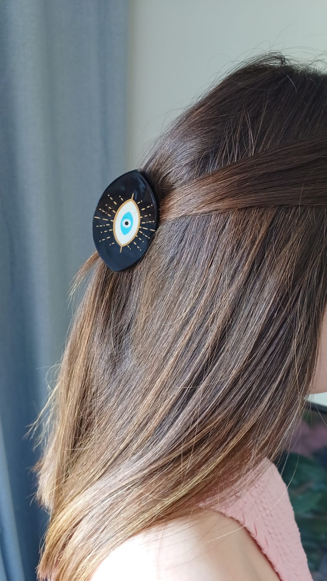 Prendedor de cabelo preto com olho azul decorativo em cabelo castanho claro