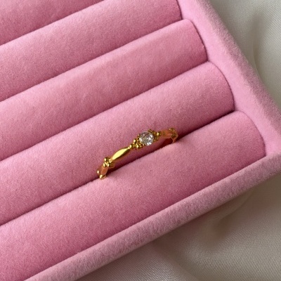 Anel dourado com pedra em caixa de veludo rosa