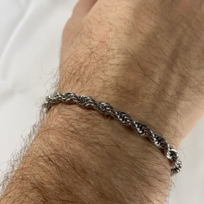 Pulseira prateada espiral no pulso de um braço peludo