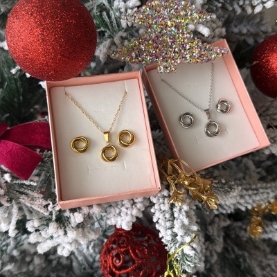 Conjuntos de joias douradas e prateadas num pinheiro de Natal nevado com bolas e enfeites vermelhos