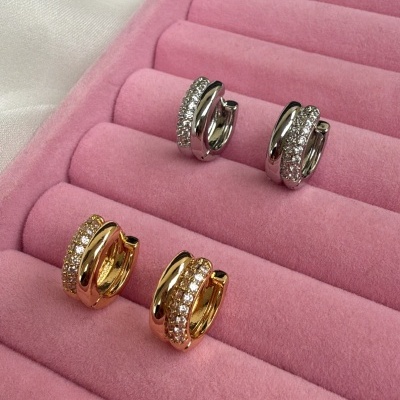 Brincos dourados e prateados com pedras em caixa de veludo rosa