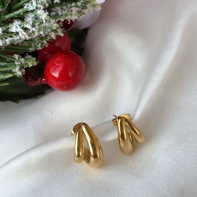 Brincos dourados sobre tecido branco com decoração natalícia