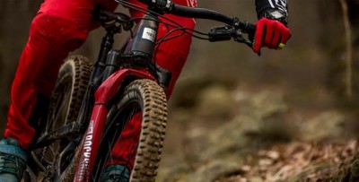 bicicleta de montanha vermelha e preto em trilho de terra com condutor de fato vermelho