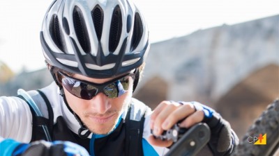 Homem de bicicleta com capacete preto e branco e óculos escuros ajustando equipamento