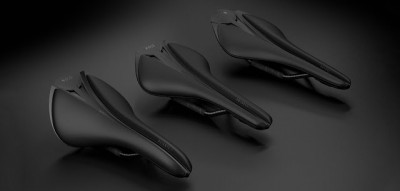 Três selins de bicicleta pretos aerodinâmicos dispostos lado a lado sobre fundo preto