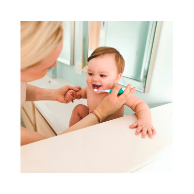 Mãe a escovar dentes de bebé com escova verde na casa de banho