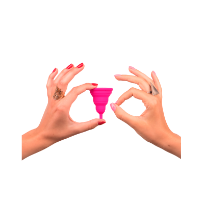 Mãos segurando coletor menstrual rosa em fundo branco