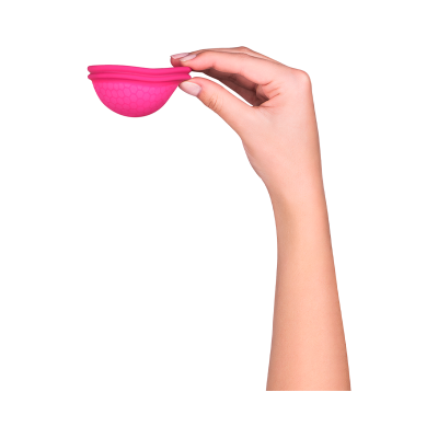 Mão segurando copo menstrual rosa com textura hexagonal