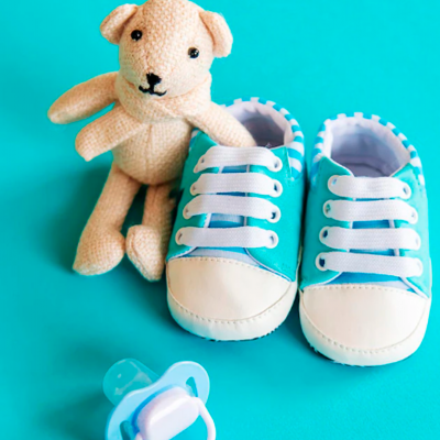 Sapatinhos de bebé azuis, ursinho de pelúcia bege e chucha branca