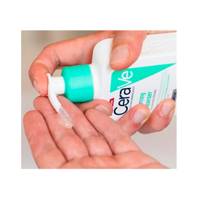 Dispenser branco e verde com gel transparente sendo aplicado na mão