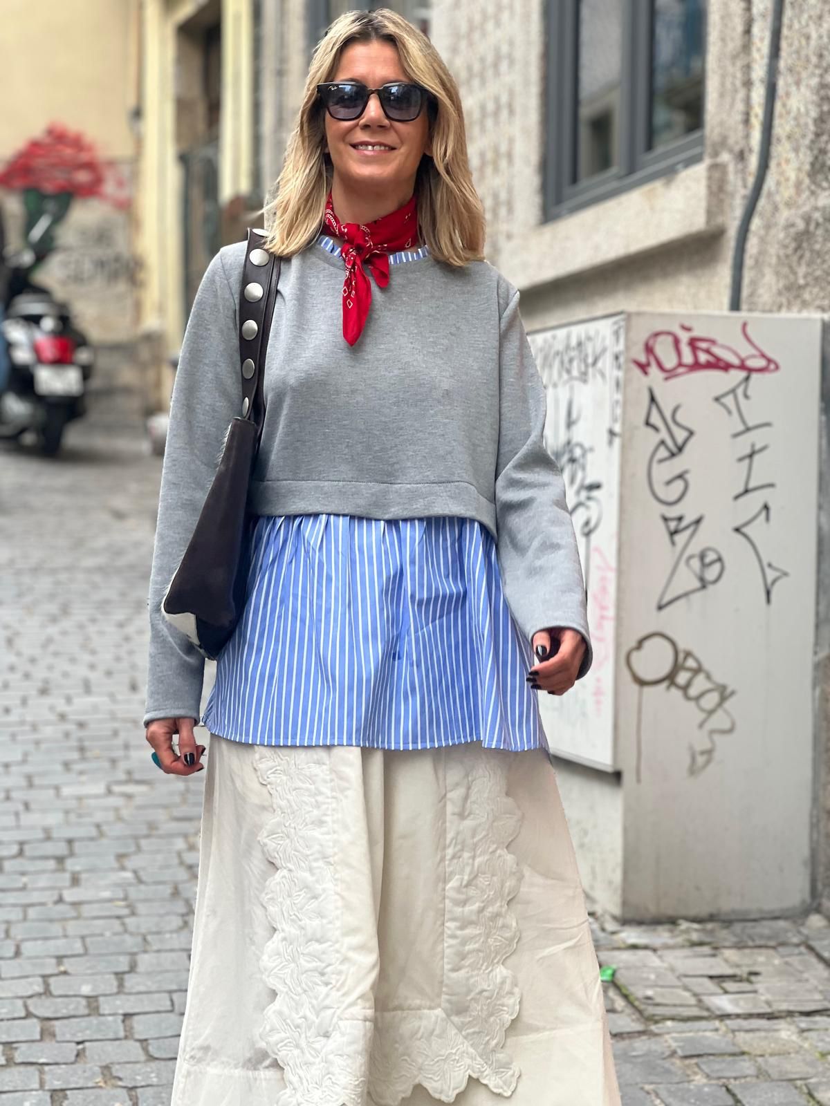 Mulher com roupa moderna numa rua de calçada com grafites nas paredes