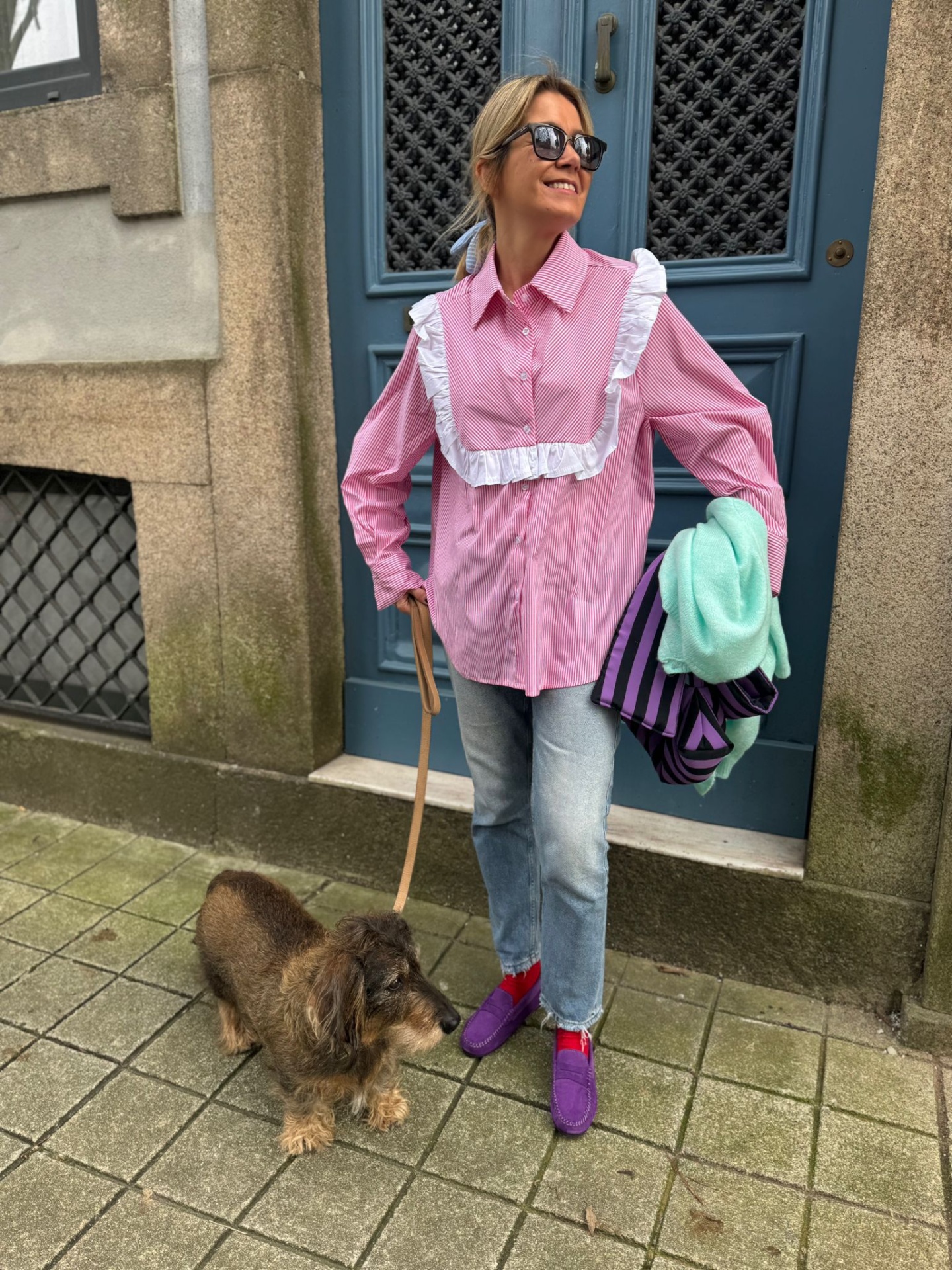 Mulher com camisa rosa e babados com cão na rua