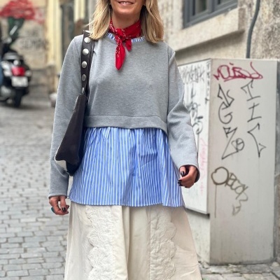 Mulher com roupa moderna numa rua de calçada com grafites nas paredes