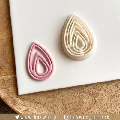 Dois cortantes em forma de gota, rosa e branco sobre superfície branca e madeira