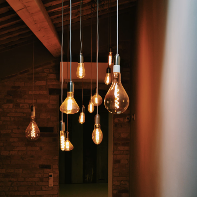 Lâmpadas pendentes vintage com filamentos visíveis em teto de madeira numa sala com parede de tijolos
