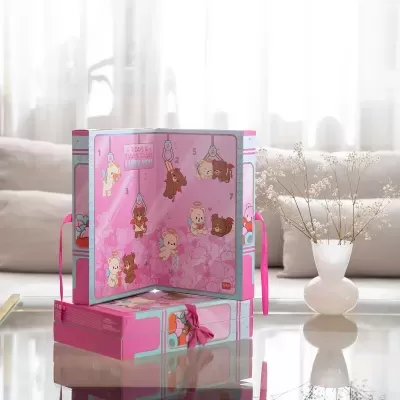 Caixa presente rosa com ilustrações de ursos e texto 7 DAYS & 7 WAYS TO SAY I LOVE YOU numa mesa com vaso branco e flores.