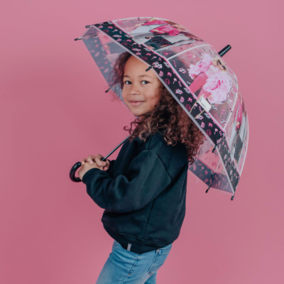 Garota com guarda-chuva transparente decorado com flores cor-de-rosa