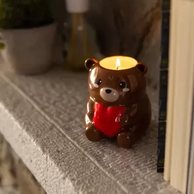 Vela em suporte de cerâmica castanho em forma de urso a segurar um coração vermelho