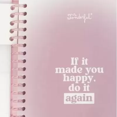 Caderno rosado com espiral e frase motivacional na capa