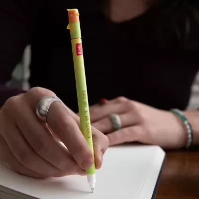 Caneta verde claro com tampa de pássaro e texto, segurada por mão com anéis sobre folha branca