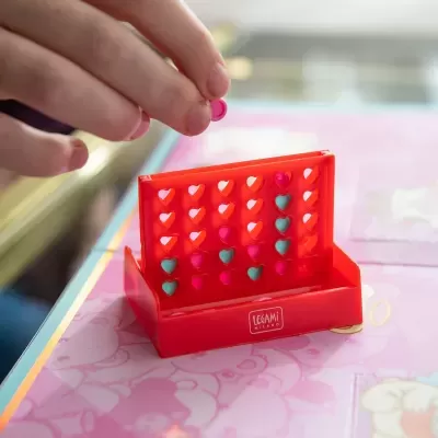 Jogo de tabuleiro LEGAMI MILANO vermelho com peças de coração rosa e azul numa mesa cor-de-rosa