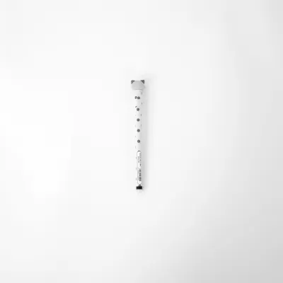 Caneta esferográfica branca com bolinhas pretas e tampa cinzenta sobre fundo branco