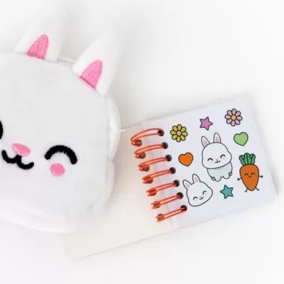 Caderno pequeno espiral com capa de coelho branco e desenhos divertidos na página aberta
