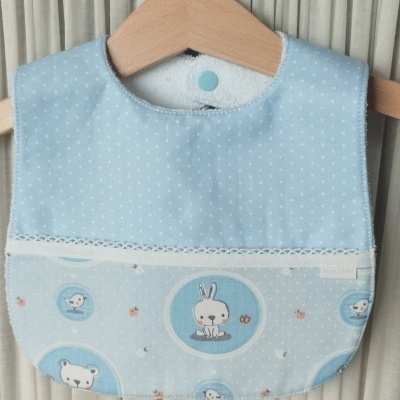 Babete azul claro para bebé com padrões de animais e poás brancos