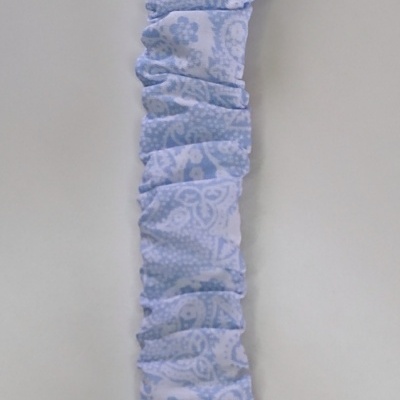 Presilha de tecido azul claro com clipe branco e fita de cetim, fundo cinzento