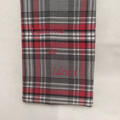 Caderno com capa xadrez cinza, vermelho e branco e texto 'Caderno de Ideias'